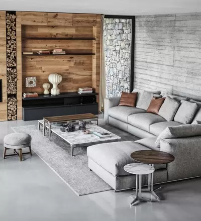 Graue Sofalandschaft vor Steinwand mit Tisch und Stühlen